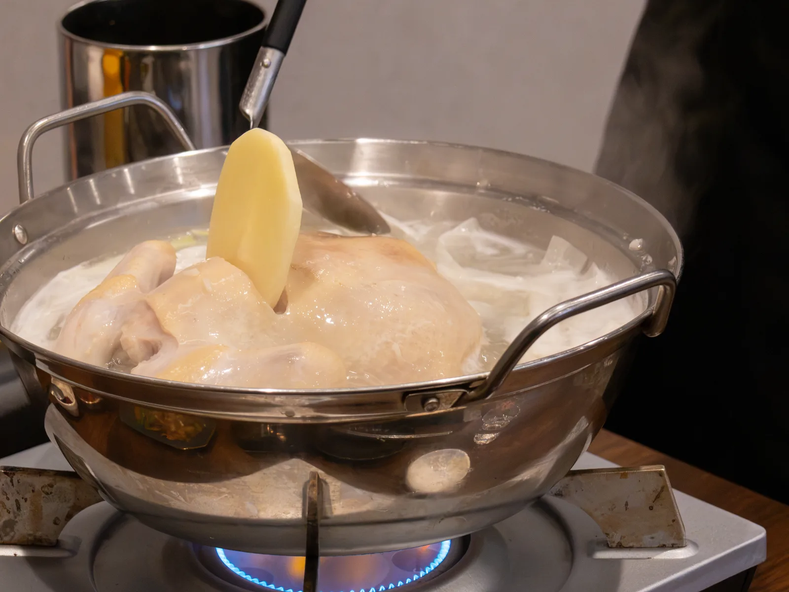 火にかけたタッカンマリ鍋で丸鶏を煮込むところ
